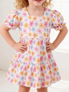 Pink floral children’s dress with puff sleeves and a ruffled hem.